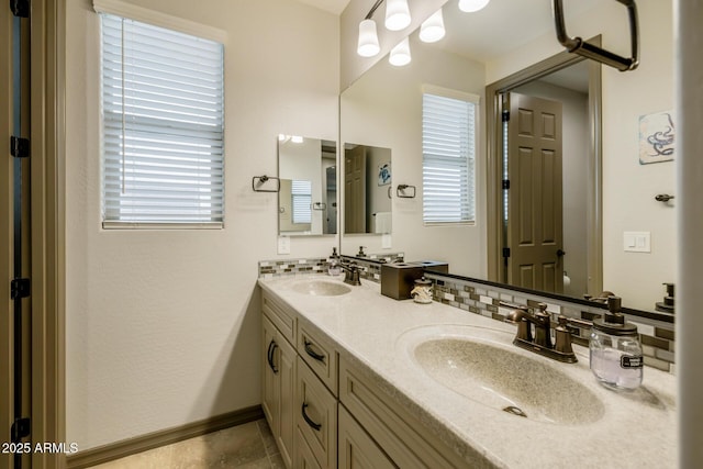 full bathroom featuring a sink, baseboards, and double vanity