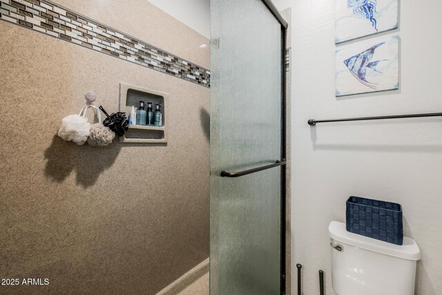 bathroom featuring toilet and a shower with door