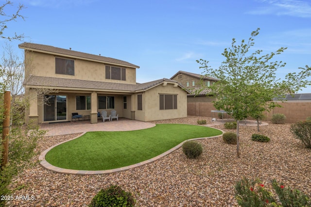 rear view of property with a patio, a yard, a fenced backyard, stucco siding, and a tiled roof