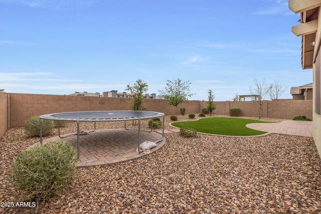 view of yard featuring a fenced backyard, a patio, and a trampoline