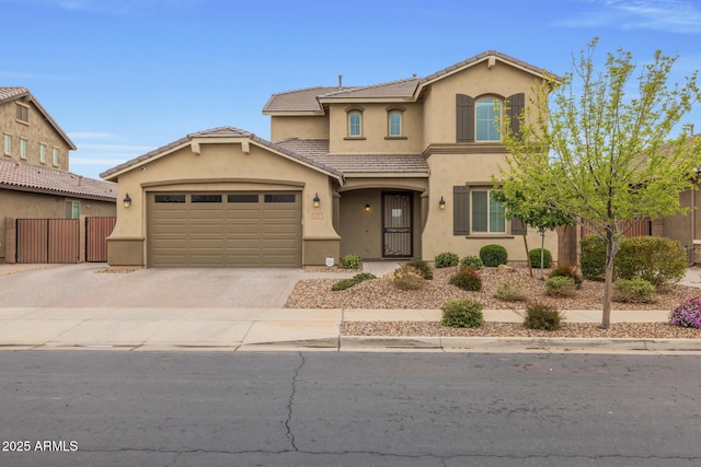 mediterranean / spanish-style house with fence, an attached garage, stucco siding, a tiled roof, and decorative driveway