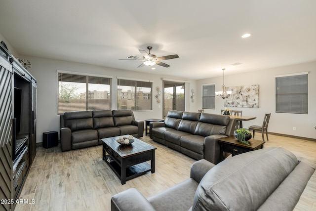 living area featuring a barn door, plenty of natural light, light wood-style floors, and baseboards