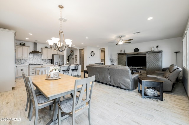 dining area featuring visible vents, ceiling fan with notable chandelier, recessed lighting, arched walkways, and light wood-style floors