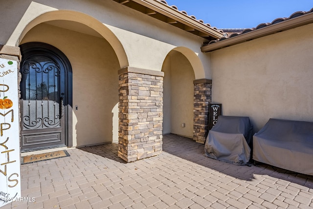 view of exterior entry with a patio area