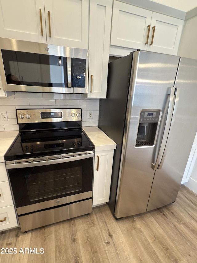 kitchen with decorative backsplash, white cabinetry, and appliances with stainless steel finishes