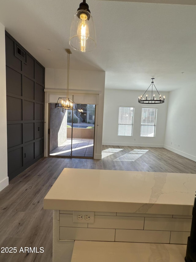 unfurnished dining area featuring an inviting chandelier, baseboards, and wood finished floors