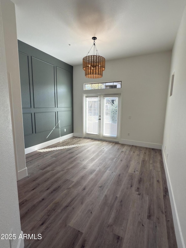 interior space featuring baseboards, a decorative wall, wood finished floors, and french doors