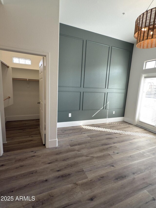 interior space featuring baseboards, a decorative wall, a closet, and wood finished floors