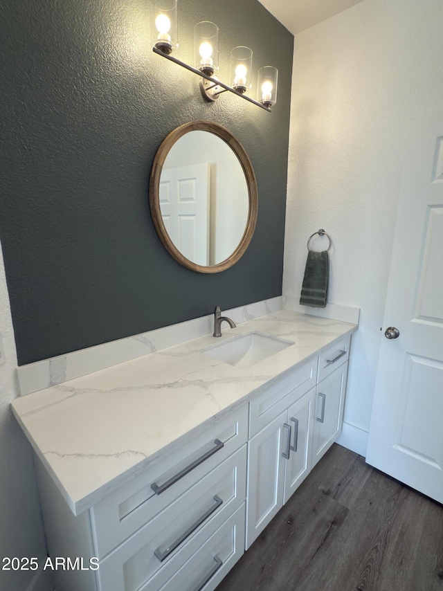 bathroom with a textured wall, wood finished floors, and vanity