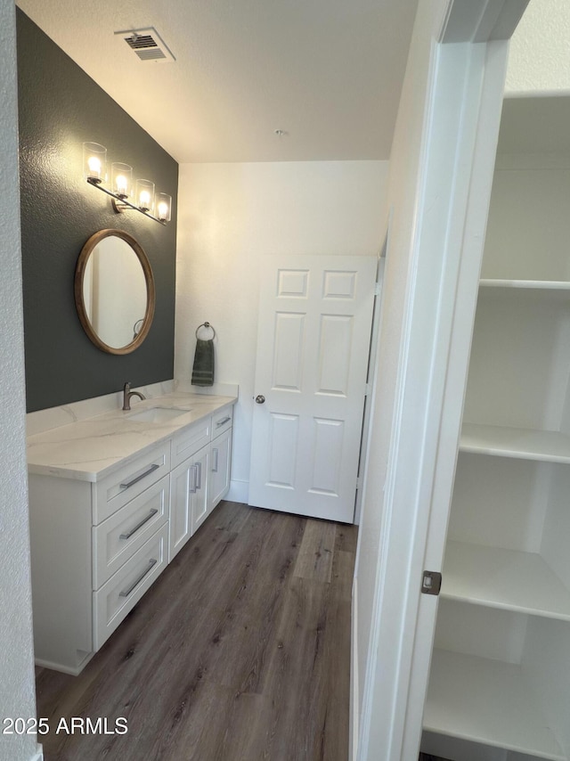 bathroom with baseboards, visible vents, wood finished floors, and vanity