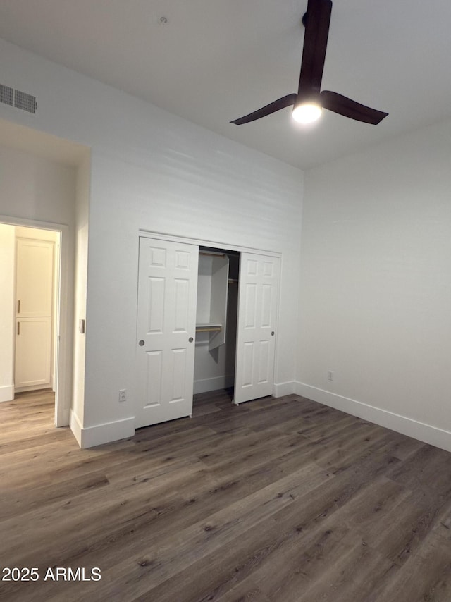 unfurnished bedroom featuring visible vents, baseboards, ceiling fan, dark wood-type flooring, and a closet