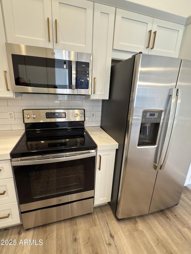 kitchen with appliances with stainless steel finishes, light wood-type flooring, and light countertops