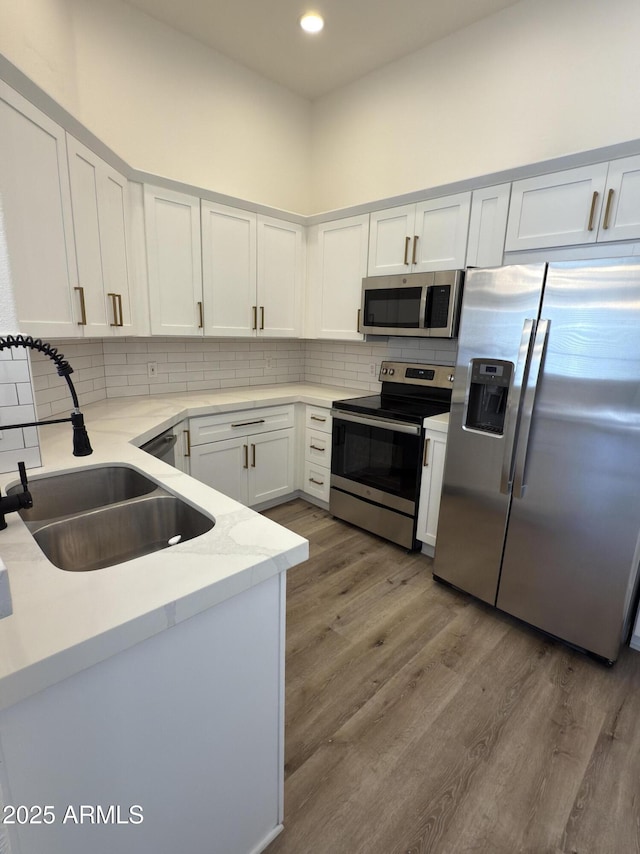 kitchen with stainless steel appliances, wood finished floors, backsplash, and a sink