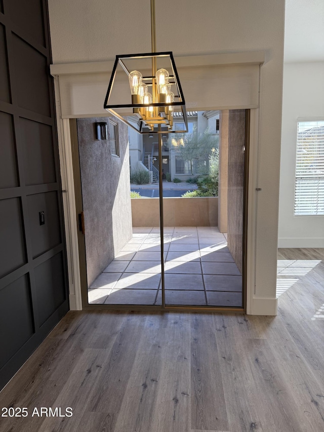 doorway featuring an inviting chandelier, baseboards, and wood finished floors