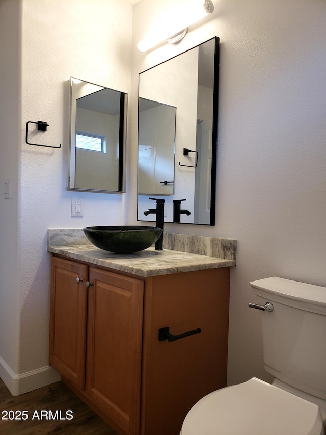 bathroom with toilet, vanity, and hardwood / wood-style flooring