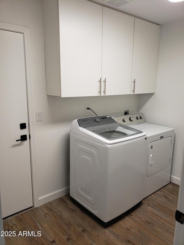 washroom with washing machine and dryer, cabinets, and dark hardwood / wood-style floors