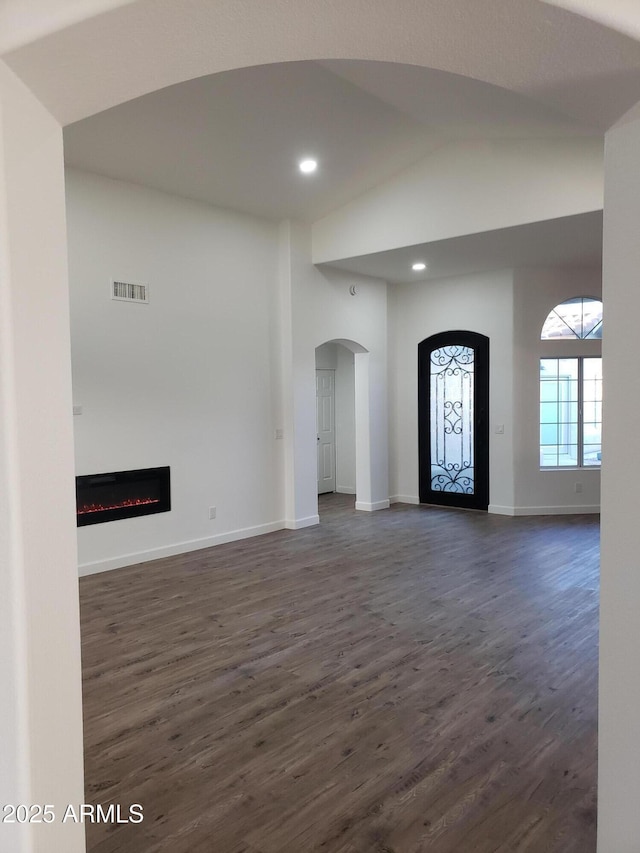 unfurnished living room featuring high vaulted ceiling and dark hardwood / wood-style floors