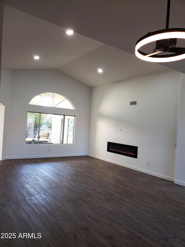 unfurnished living room featuring dark wood-type flooring and lofted ceiling