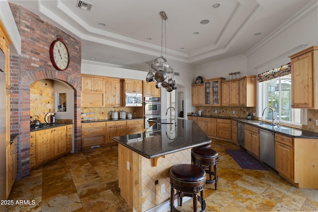 kitchen featuring a kitchen island with sink, stainless steel appliances, a sink, visible vents, and a raised ceiling