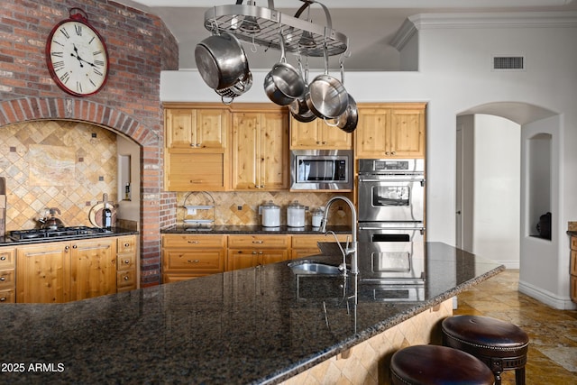 kitchen featuring stainless steel appliances, visible vents, backsplash, ornamental molding, and a sink