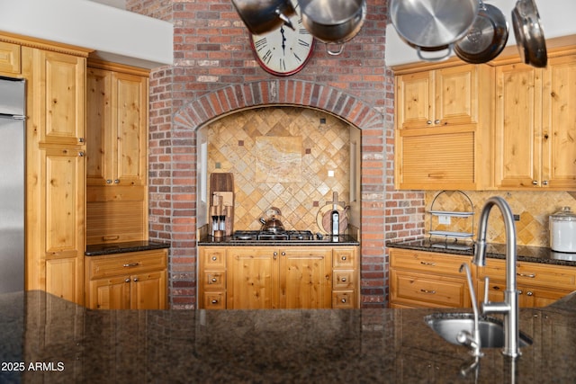 kitchen with dark stone counters, stainless steel appliances, a sink, and decorative backsplash