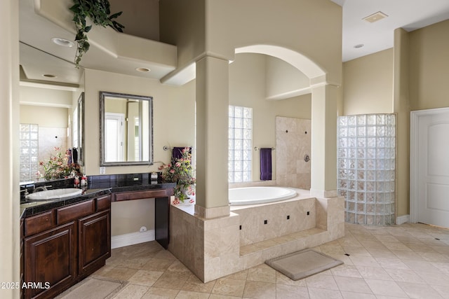 bathroom with a towering ceiling, tile patterned floors, vanity, ornate columns, and a bath