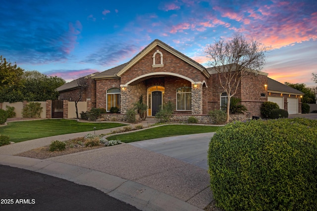 view of front facade with a garage, driveway, a lawn, fence, and brick siding