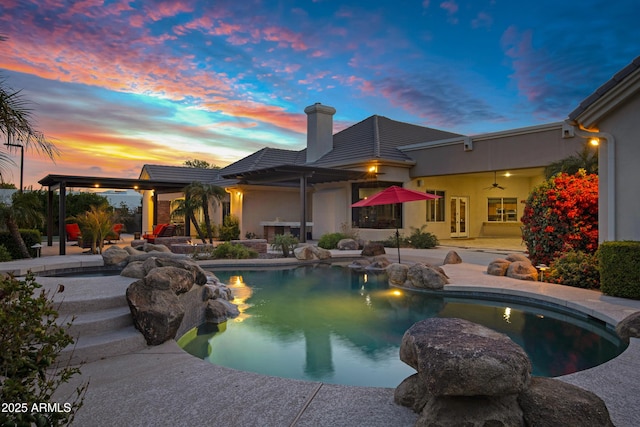 pool at dusk with a patio area and an outdoor pool