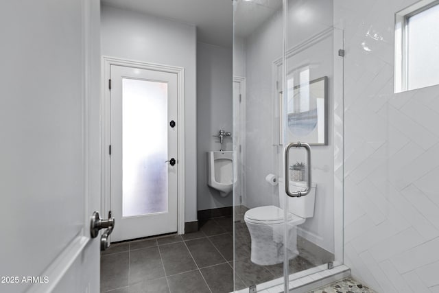 bathroom featuring a shower with door, tile patterned flooring, toilet, and a healthy amount of sunlight