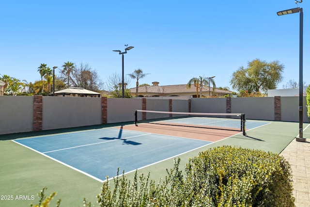 view of tennis court with community basketball court and fence