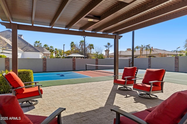 view of patio with a tennis court and fence