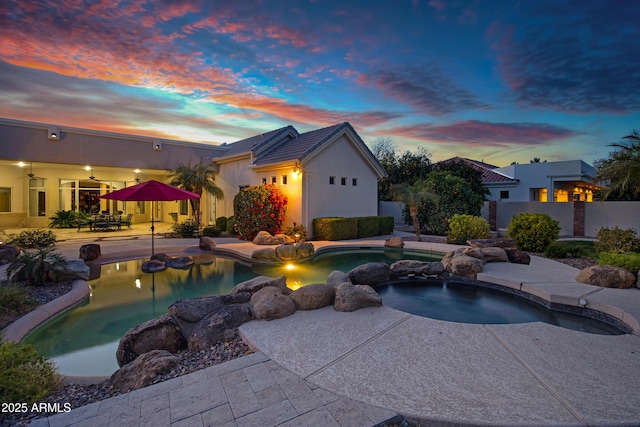 pool at dusk featuring a patio area, fence, a ceiling fan, and a fenced in pool