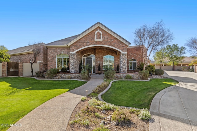 view of front of home featuring a gate, brick siding, and a front lawn