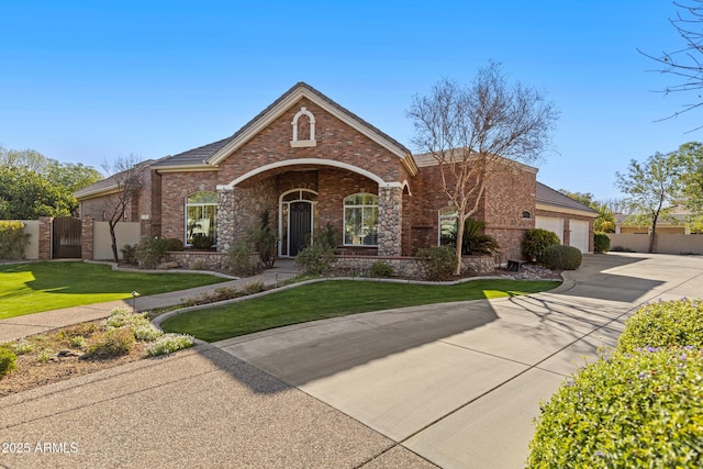 view of front of home with an attached garage, brick siding, driveway, a gate, and a front yard