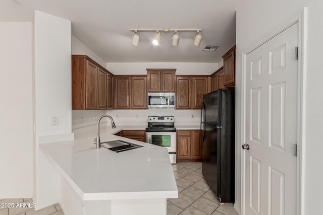 15429 W Ventura St, Surprise, AZ 85379 - kitchen featuring stainless steel appliances, light tile patterned floors, a peninsula, light countertops, and brown cabinetry