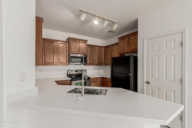 15429 W Ventura St, Surprise, AZ 85379 - kitchen featuring stainless steel appliances, light countertops, brown cabinets, and a peninsula