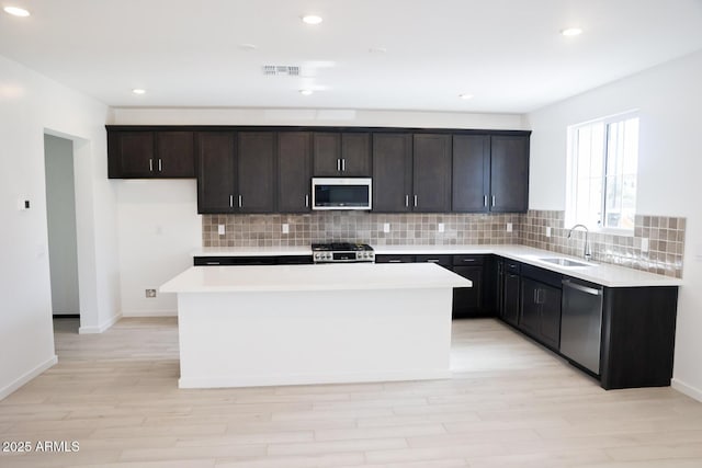 kitchen featuring visible vents, a sink, tasteful backsplash, a kitchen island, and appliances with stainless steel finishes