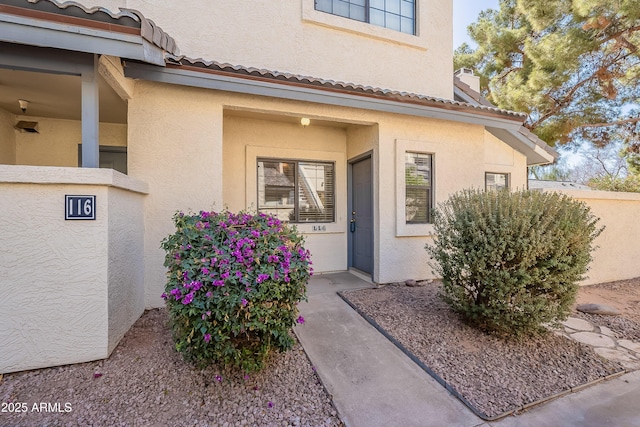 property entrance with a tiled roof, a chimney, and stucco siding