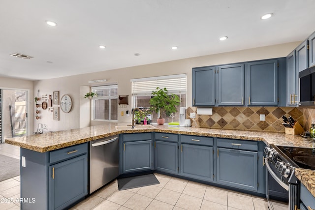 kitchen featuring visible vents, a peninsula, blue cabinetry, a sink, and appliances with stainless steel finishes