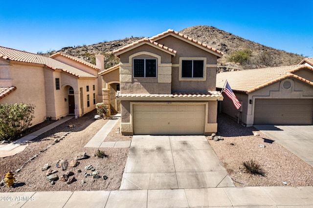 view of front of home with concrete driveway, a tiled roof, a garage, and stucco siding