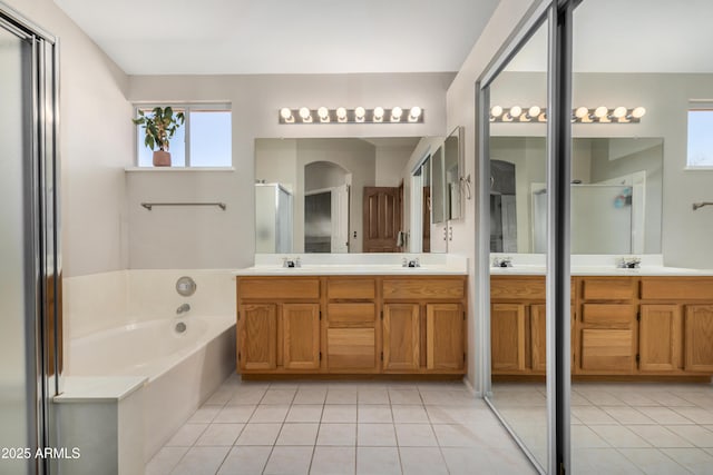 bathroom featuring tile patterned floors, a garden tub, a shower stall, and double vanity