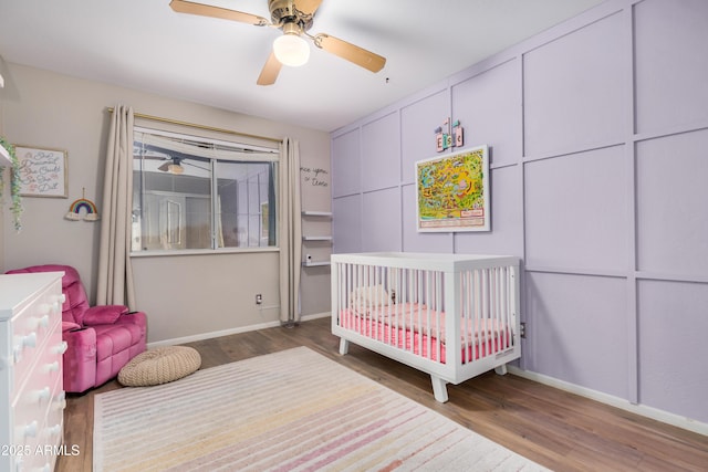 bedroom with a ceiling fan, wood finished floors, and baseboards