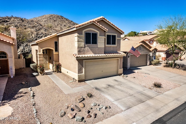 view of front of house with fence, stucco siding, concrete driveway, a tiled roof, and a mountain view