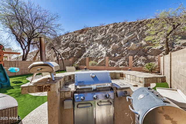 view of patio / terrace with exterior kitchen, a fenced backyard, and grilling area