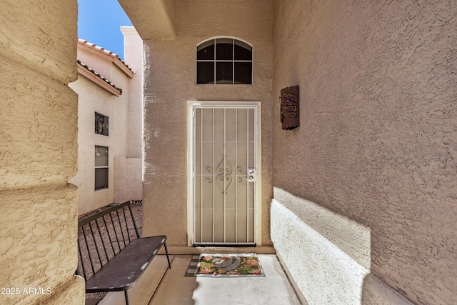 doorway to property with stucco siding and a tile roof