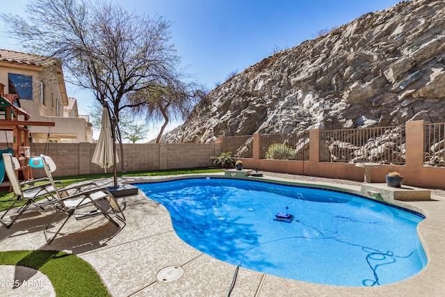 view of pool with a patio area, a fenced in pool, a fenced backyard, and a playground