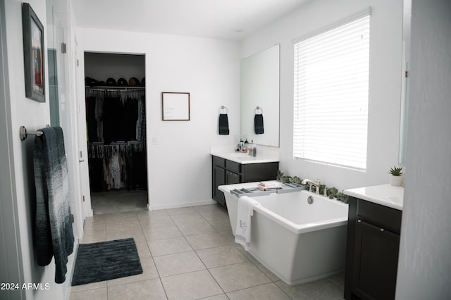 bathroom with tile patterned floors, plenty of natural light, vanity, and a bath