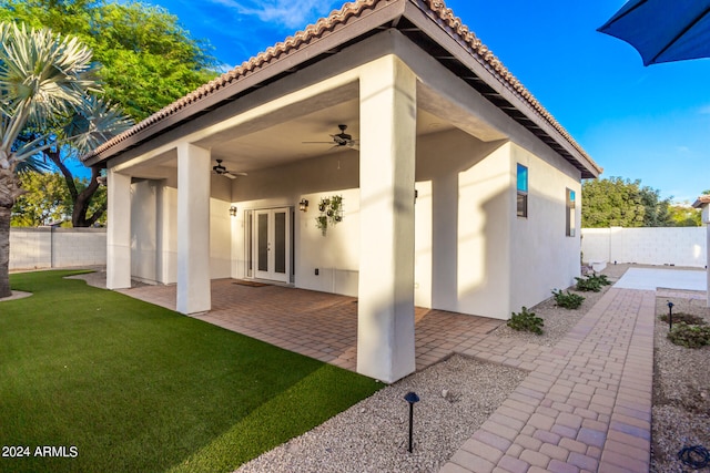 rear view of house featuring ceiling fan, a patio area, a yard, and french doors