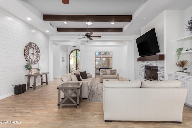 living room with beam ceiling, ceiling fan, a fireplace, and light hardwood / wood-style floors