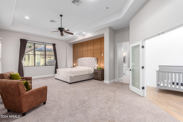 carpeted bedroom featuring a raised ceiling and ceiling fan